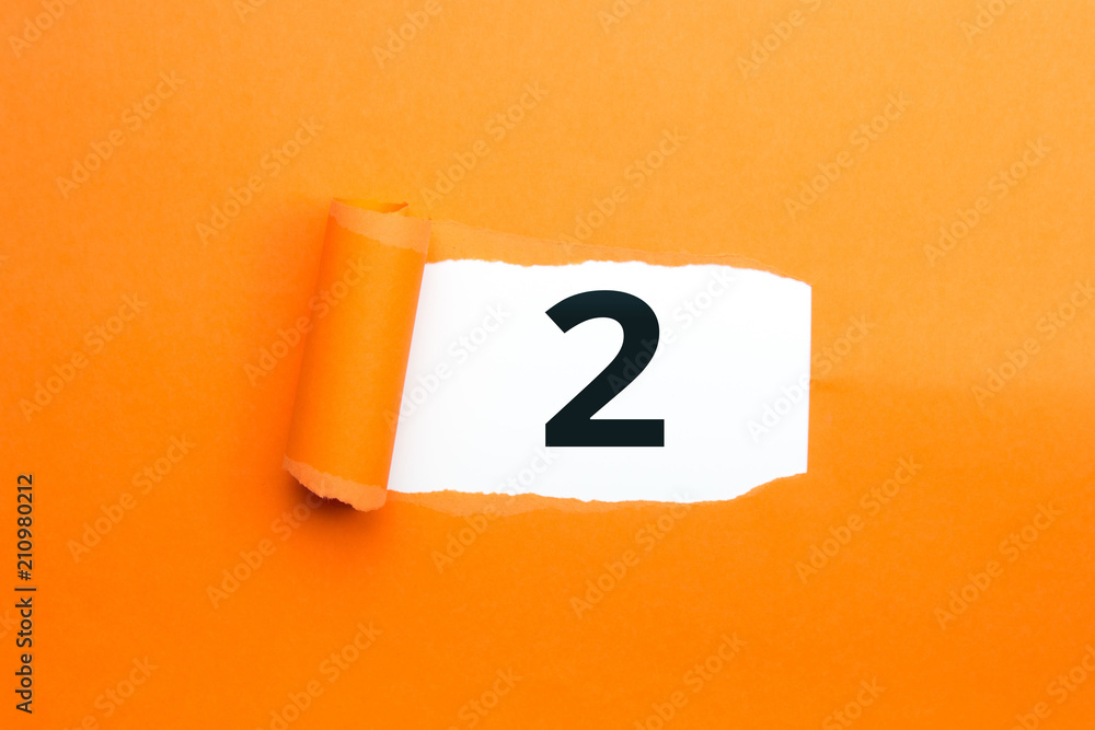 Zahl zwei - 2 verdeckt unter aufgerissenem orangen Papier Zahl zwei - 2 verdeckt unter aufgerissenem orangen Papier