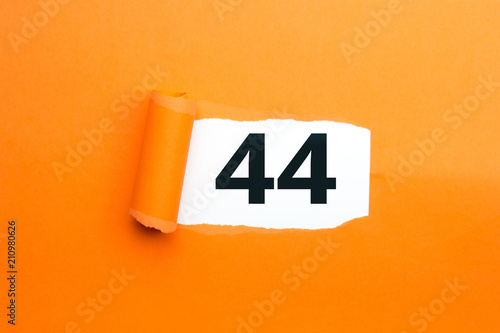 Zahl vierundvierzig - 44 verdeckt unter aufgerissenem orangen Papier photo