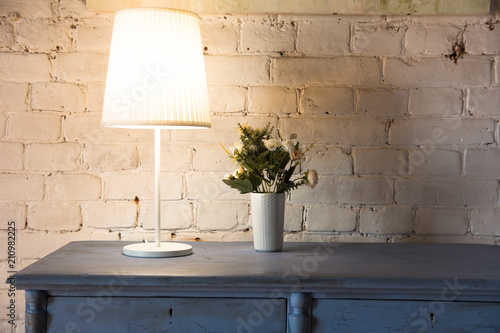 Lamp and bouquet with flowers on an old chest of drawers