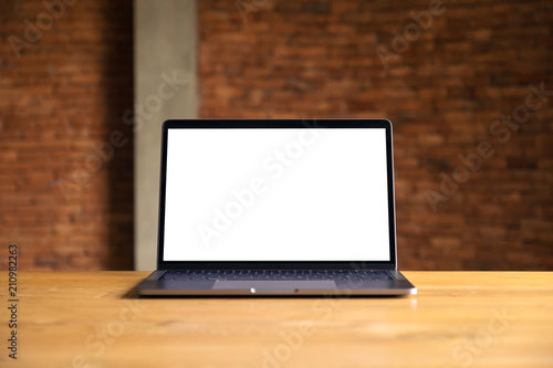 Mockup image of laptop with blank white desktop screen on wooden table with concrete wall background