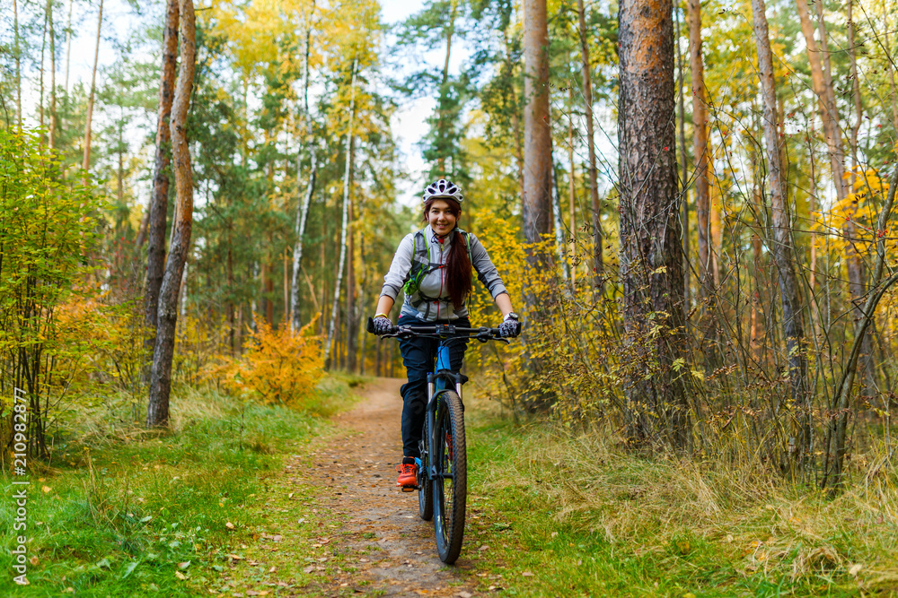 Photo of girl in helmet riding bike in autumn