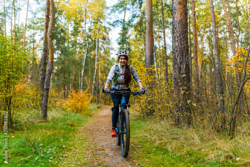 Photo of girl in helmet riding bike in autumn
