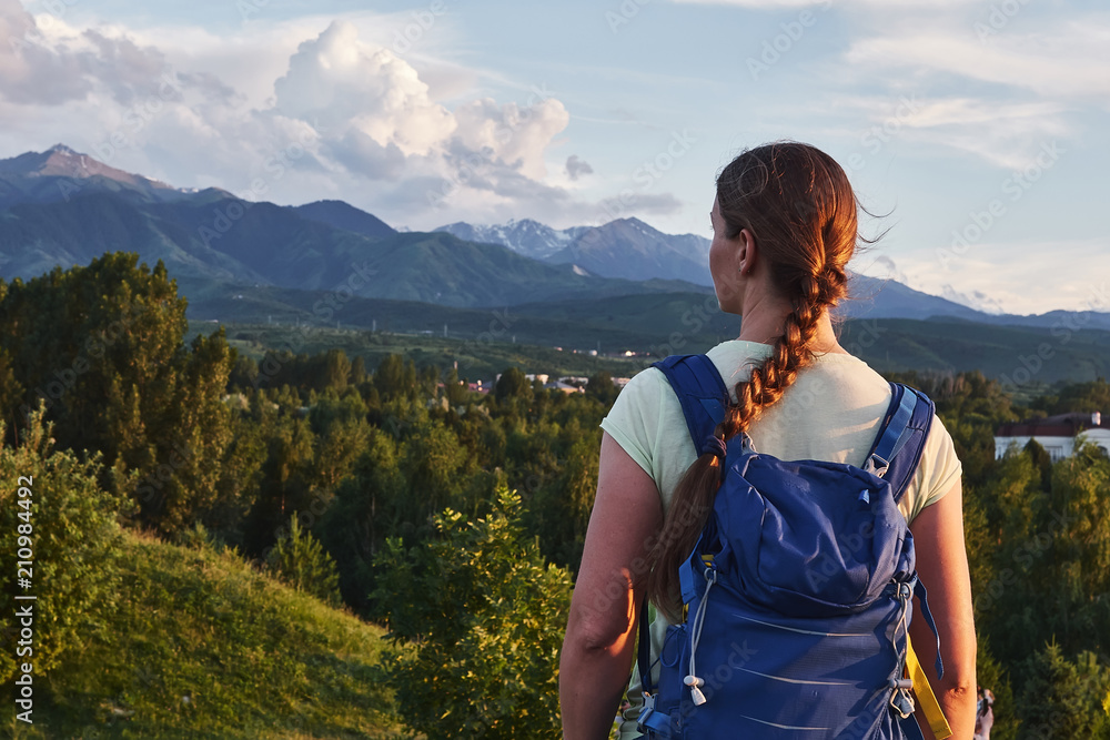 Naklejka premium Young tourist woman looking at the peaks of the Almaty mountain. Almaty, Kazakhstan
