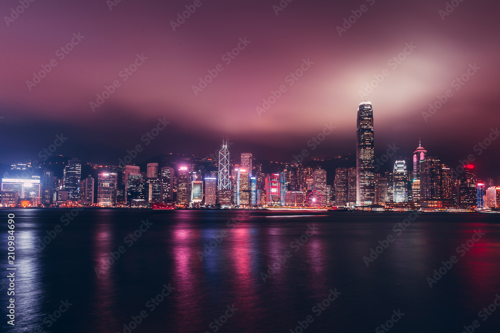 Fototapeta premium Hong Kong skyline on Victoria Harbour with moody mist and clouds in sky