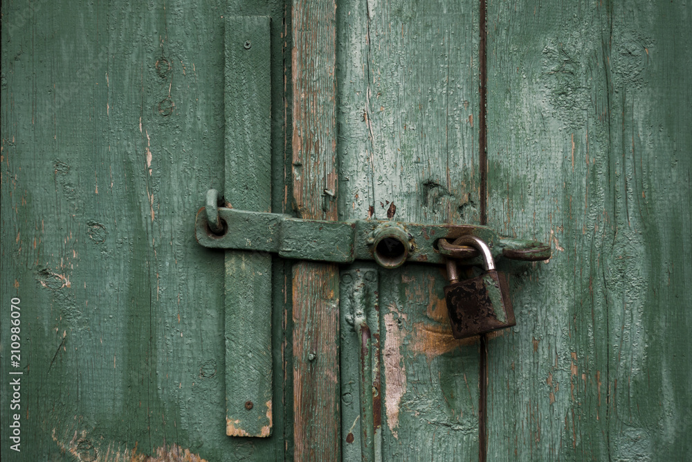 Fragment of old green wooden door with padlock. Vintage timber texture background. Fragment of old green wooden door with padlock. Vintage timber texture background.