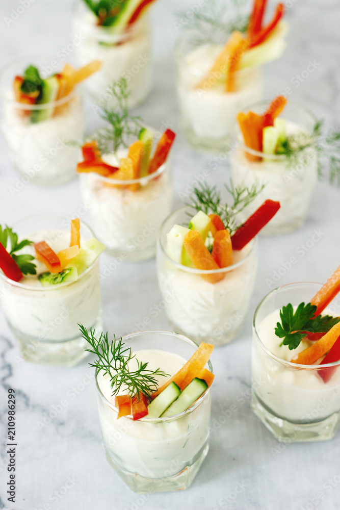 Snack in a glass with fresh cream and various vegetables on a light background. Snack in a glass with fresh cream and various vegetables on a light background.