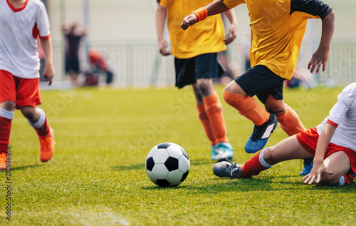 Young Junior Football Match. Players Running and Kicking Football Ball © matimix