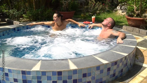 Couple relaxes in the hot tub. Woman gets up and goes