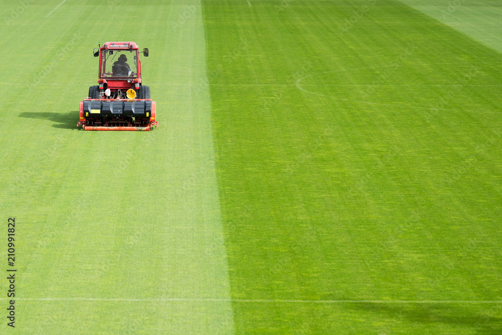 Fototapeta premium Man in tractor aerating a soccer field