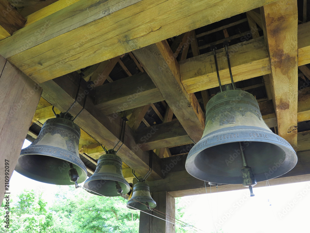 Bronze bells on wooden beams in church bell tower.