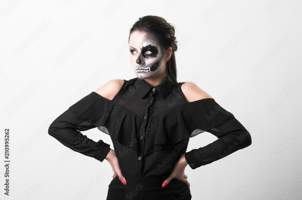 Studio portrait of beauty brunette woman wearing black clothes with scary greasepaint on face standing on white background Studio portrait of beauty brunette woman wearing black clothes with scary greasepaint on face standing on white background