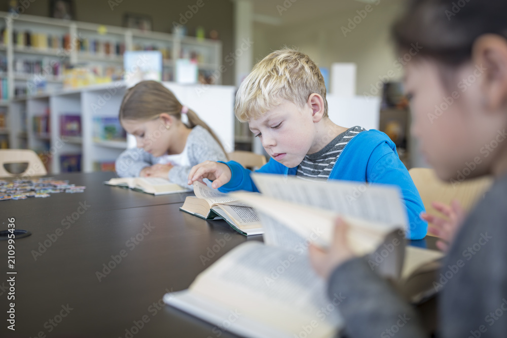 Pupils reading books on table in school break room Pupils reading books on table in school break room