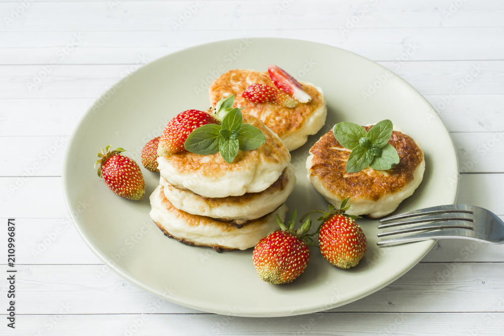 Curd pancakes with strawberries and mint on a plate Curd pancakes with strawberries and mint on a plate