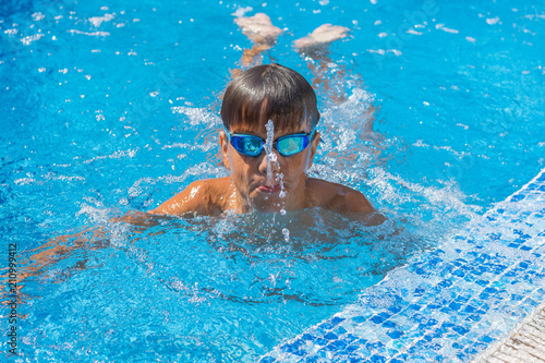 Boy spitting water, summer games at pool. Copy space.