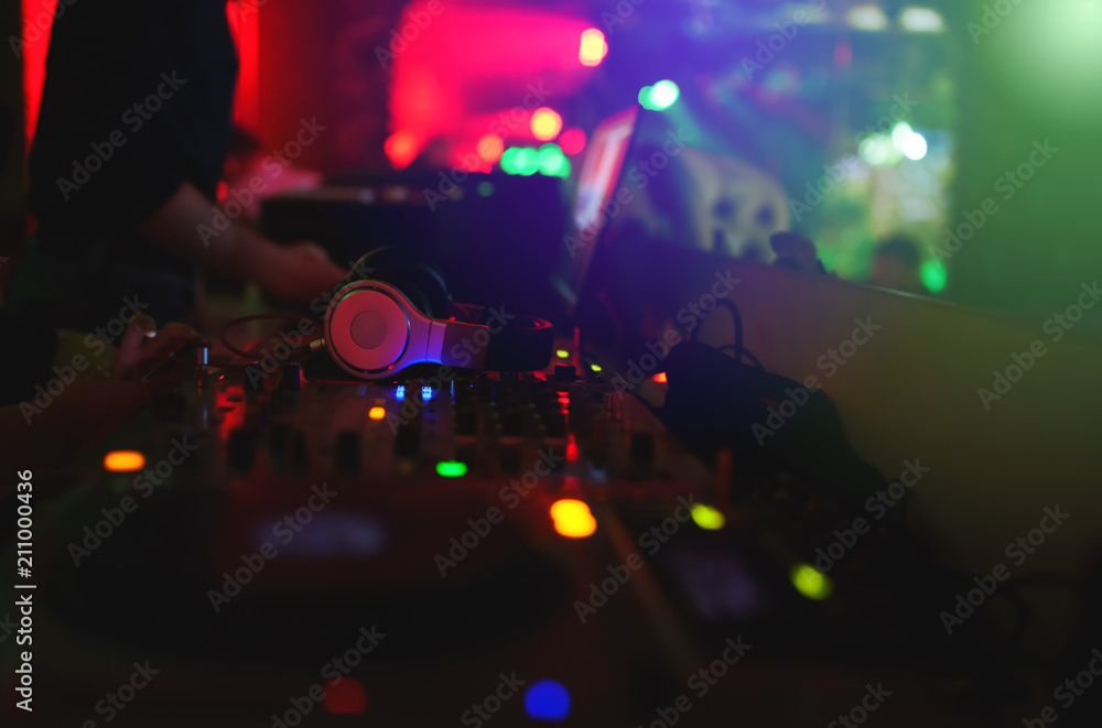 the hands of a young DJ operate a remote in a nightclub creating contemporary music