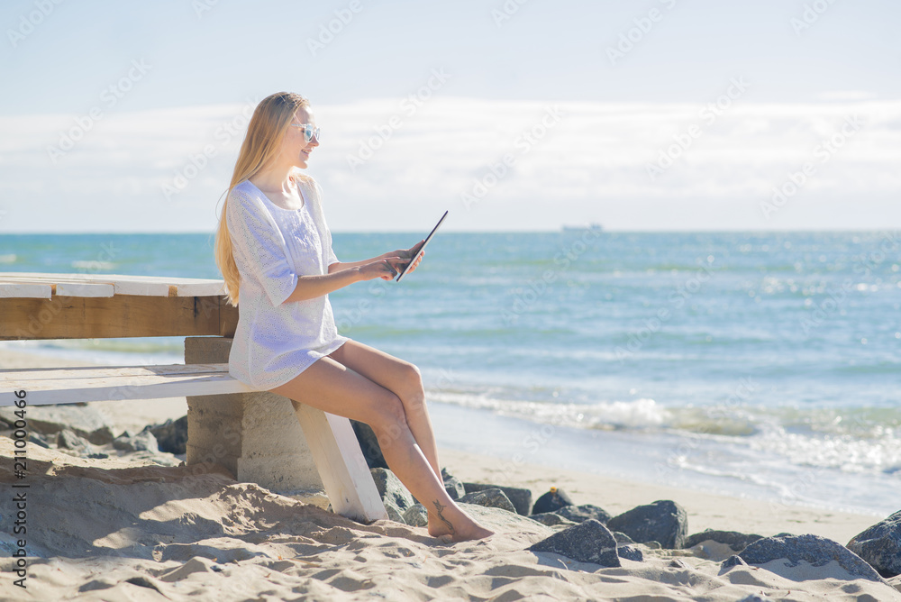 Young woman with tablet on the seaside in sunny day