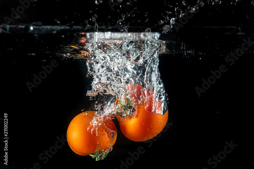 Tomatoes splashing in water on a black background