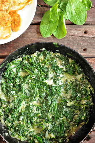 Spinach in a cream sauce in a pan on a wooden background