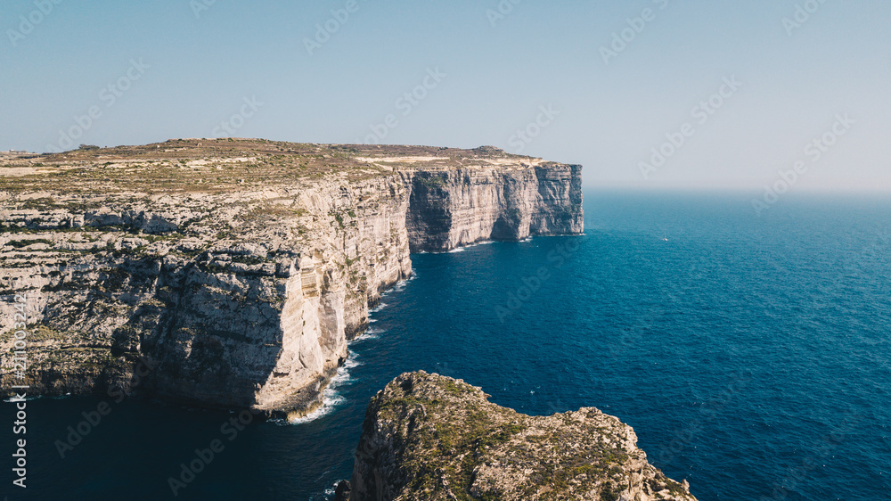 Beautiful aerial view of dramatic high precipice with beautiful sea view. Drone top view shot of dangerous stony cliffs on sunny day. Gozo island, Malta