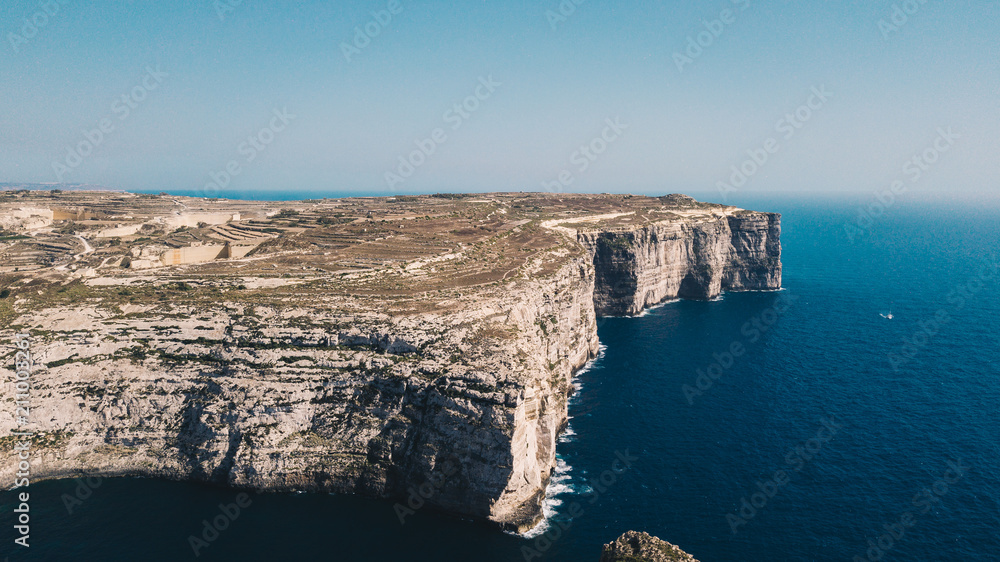 Beautiful aerial view of dramatic high precipice with beautiful sea view. Yacht sailing boat in the sea. Drone top view shot of dangerous stony cliffs. Gozo island, Malta