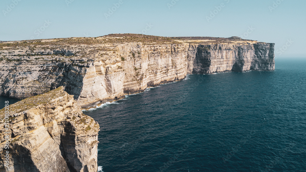 Beautiful aerial view of dramatic high precipice with beautiful sea view. Drone top view shot of dangerous stony cliffs. Gozo island, Malta Beautiful aerial view of dramatic high precipice with beautiful sea view. Drone top view shot of dangerous stony cliffs. Gozo island, Malta
