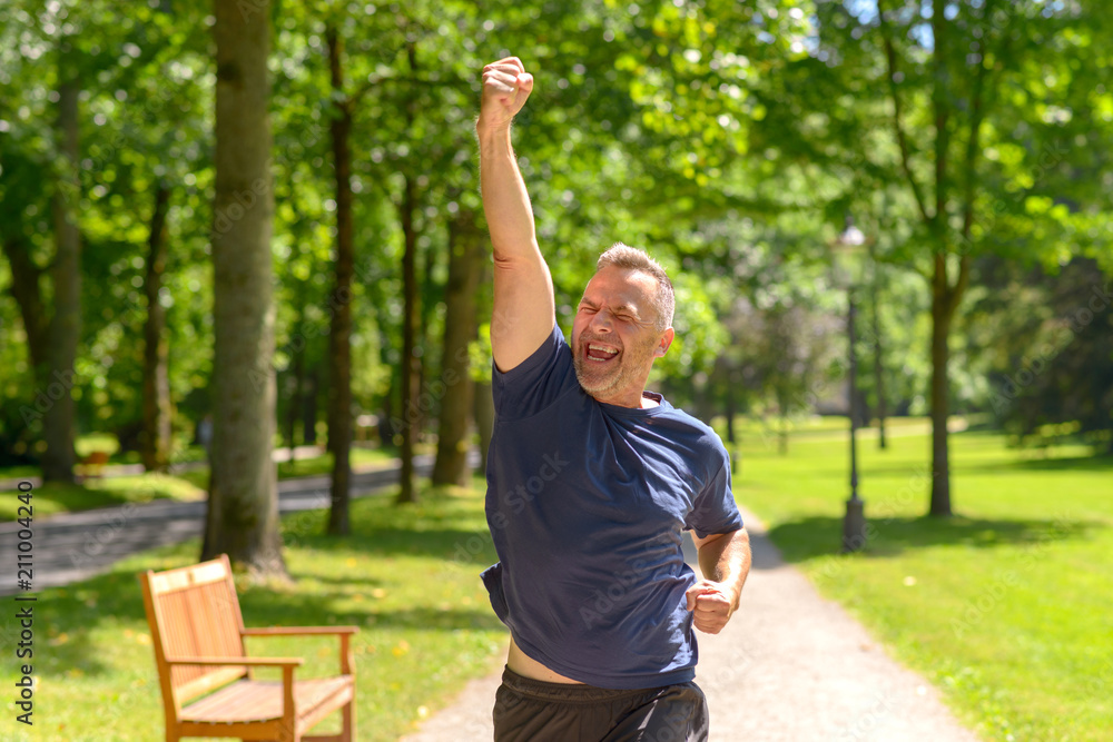 Mature man running in park with winning gesture Mature man running in park with winning gesture