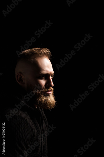male portrait of a guy with a beard on a black background close-up