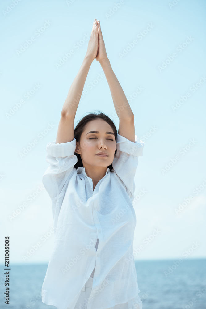 concentrated asian woman with closed eyes standing in asana vrikshasana (tree pose) by sea concentrated asian woman with closed eyes standing in asana vrikshasana (tree pose) by sea