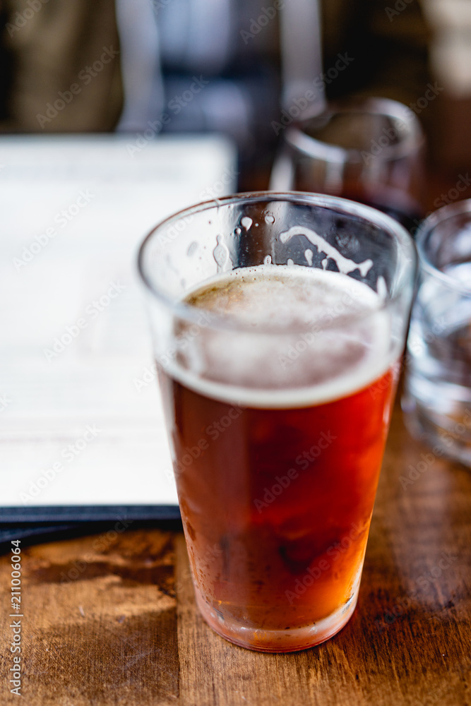 IPA beer next to a window at a rustic bar