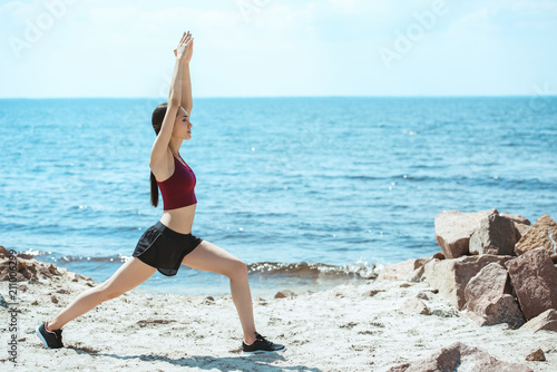 young asian sportswoman exercising on beach in front of sea
