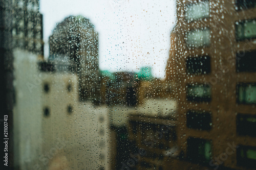Rain drop covered window with city buildings in the background