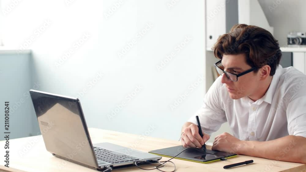 Casual male designer using graphics tablet in a bright office Casual male designer using graphics tablet in a bright office