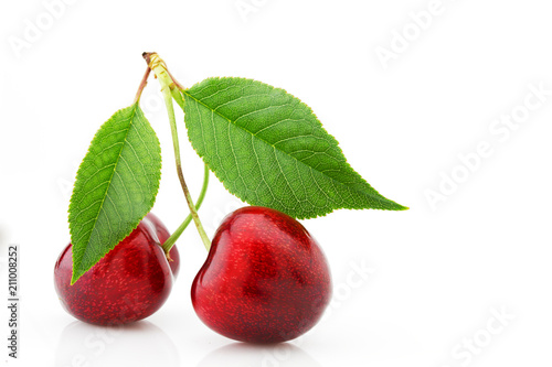 Ripe cherries with green leaves close-up, isolated on white background.