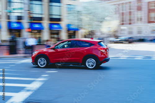 A motion pan red SUV driving through a city