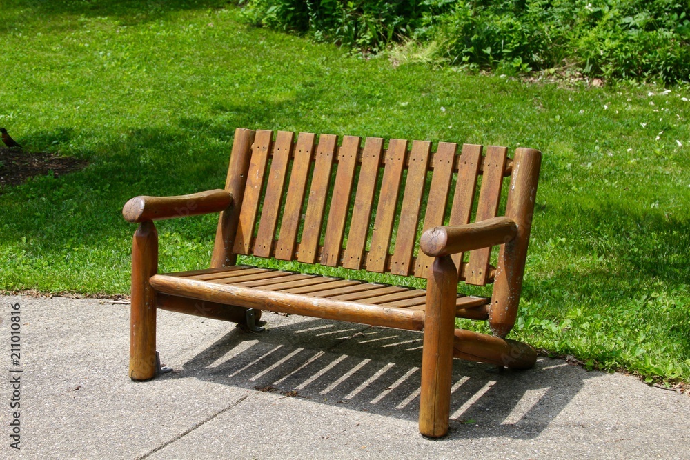 A wood park bench in the park on a close up view.