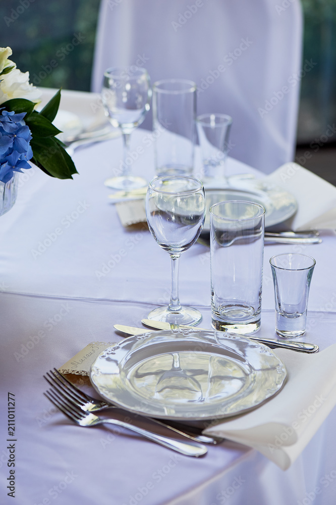 Classic table setting.Appliances, glasses, white tablecloth and plate