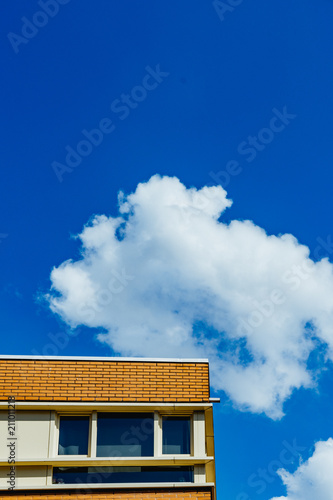 Simple house with a fluffy white cloud in the background © Dan