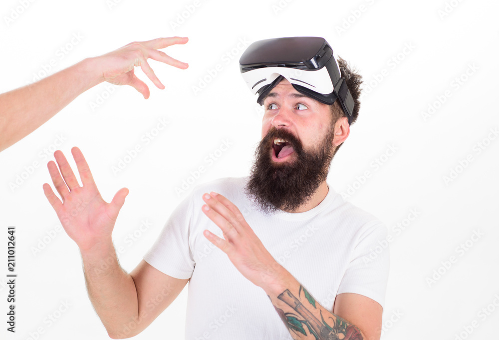 Man with beard in VR glasses scared of male hand on white background.  Bearded man protecting