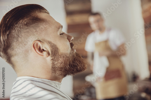 Close-up of man's face with a beard while he is waiting for a barber. Photo in vintage style