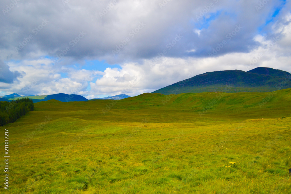 View of Scottish Highlands, in Scotland. Beautiful green grass field in middle of mountains