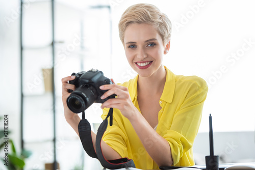 portrait of female photographer holding camera at table in photostudio