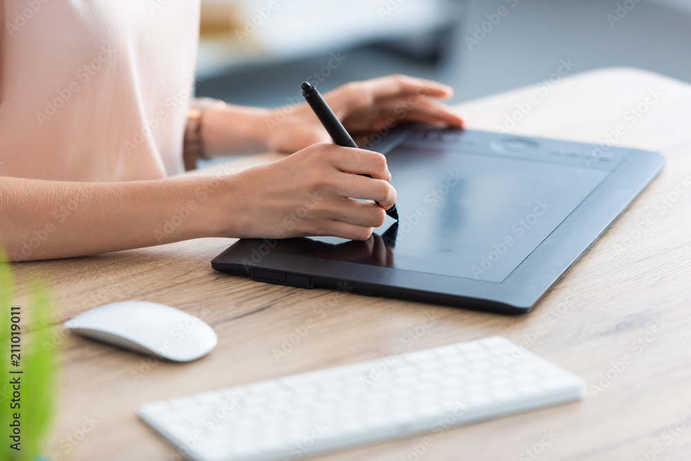Fototapeta premium cropped image of female freelancer drawing on graphic tablet at table in home office