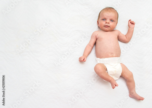 infant baby in a diaper on a white background looks at the camera. place for text