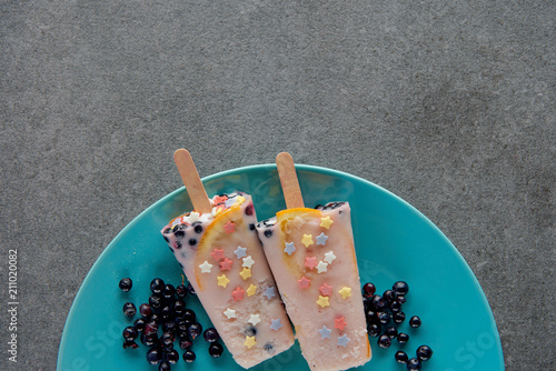 top view of sweet cold popsicles with berries on plate on grey