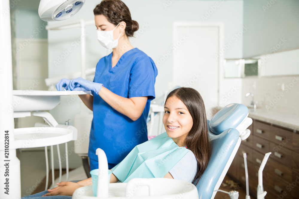 Smiling Girl Sitting On Chair While Dentist Working In Clinic Smiling Girl Sitting On Chair While Dentist Working In Clinic