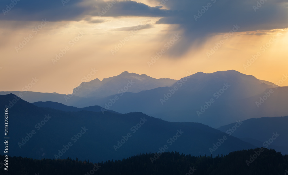Mountain ridges at sunset against the sky with clouds