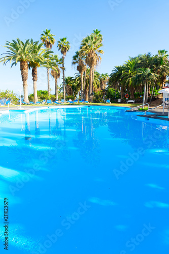 blue tiled pool with sun beams and palm trees