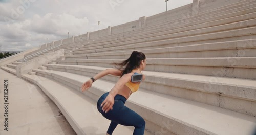 Young athletic woman exercising and jumping on urban stadium stairs photo