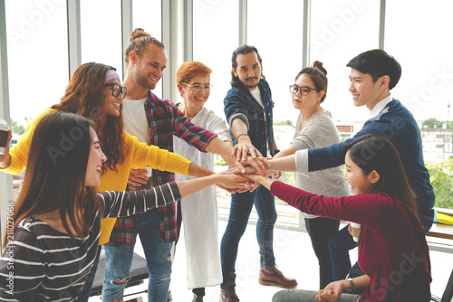 Canvas Print Multiethnic young team stack hands together as unity and teamwork in modern office
