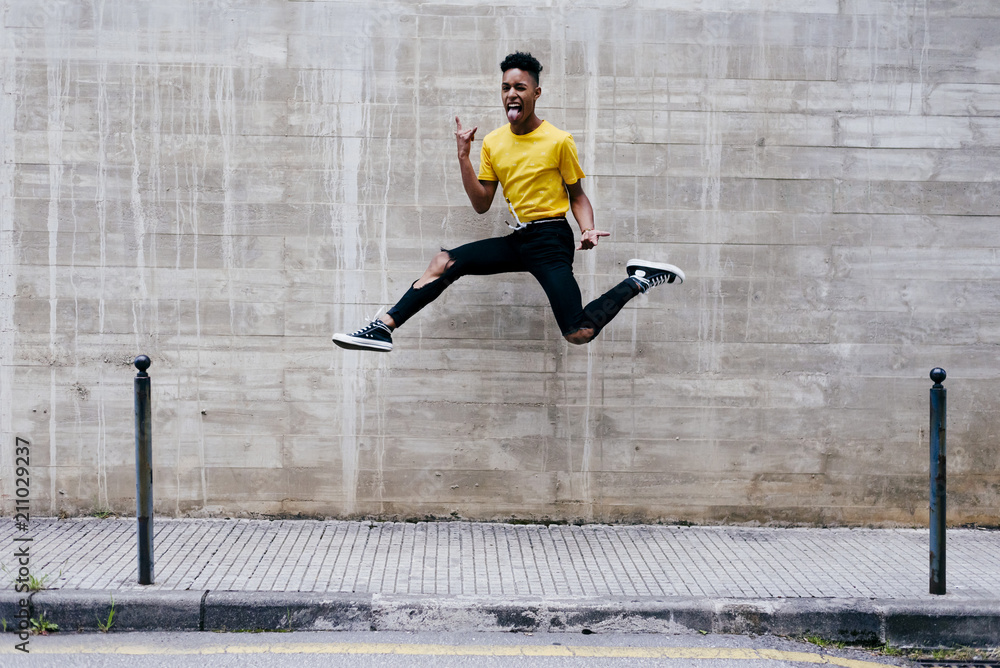 Excited ethnic teenager jumping on street Excited ethnic teenager jumping on street
